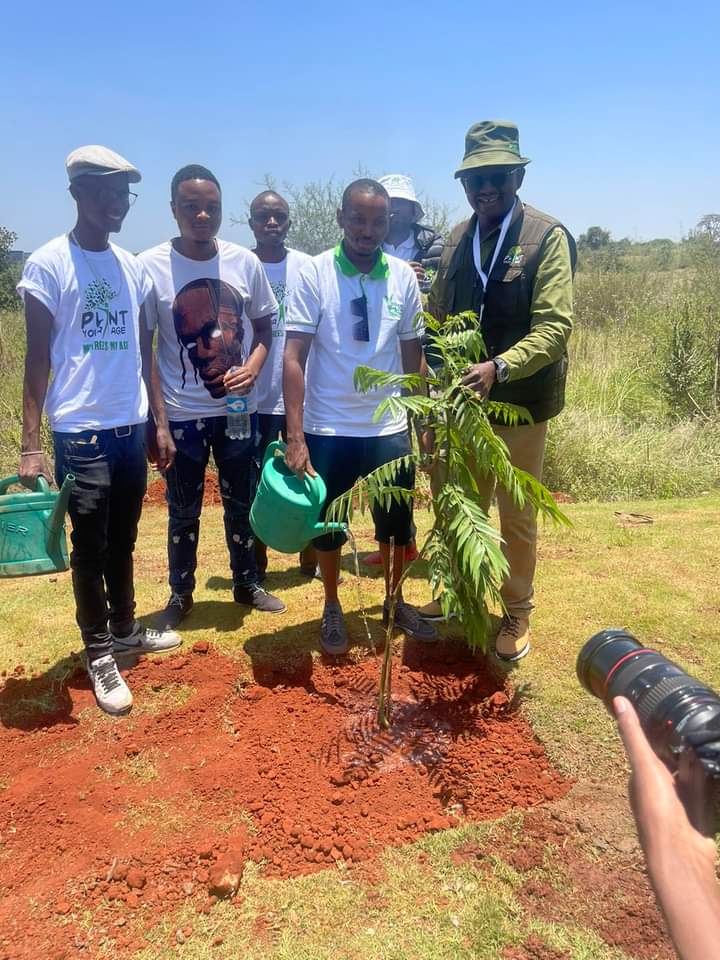 Dr Isaac Kalua Green and young planters with a newly planted tree at Tatu City